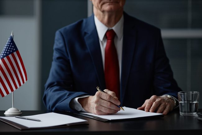 Caucasian Senior Male Politician Signing Documents during Business Meeting
