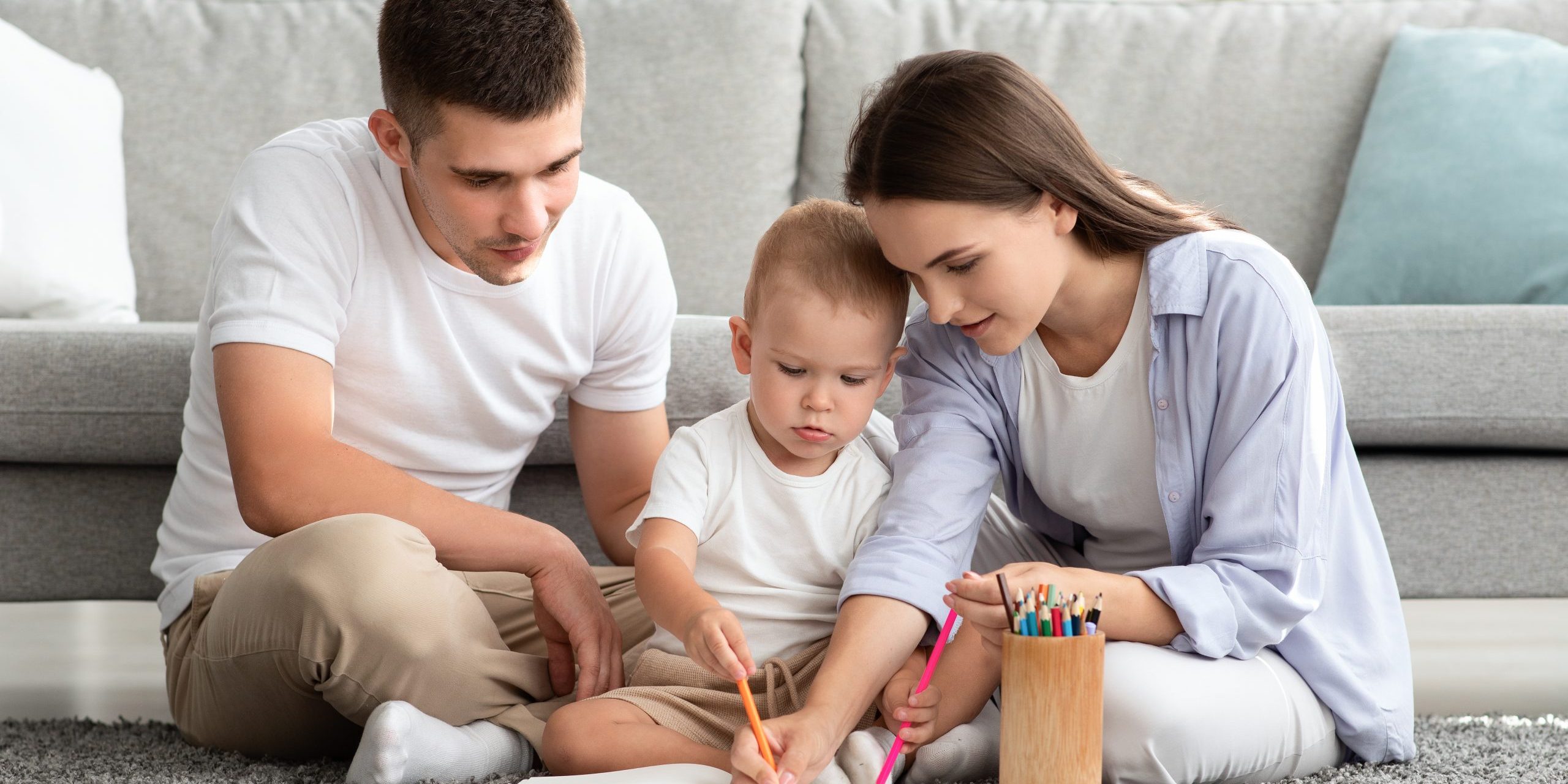 Young Parents With Adorable Infant Baby Drawing Together At Home
